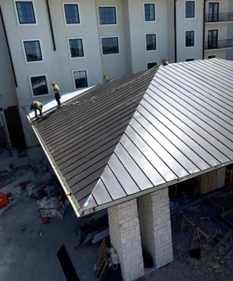 Crew installing standing seam metal roof panels on a commercial project in Mandan